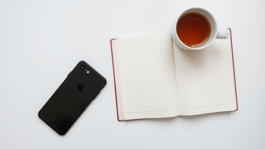 Flat lay of phone face down next to tea and journal representing emotional detachment