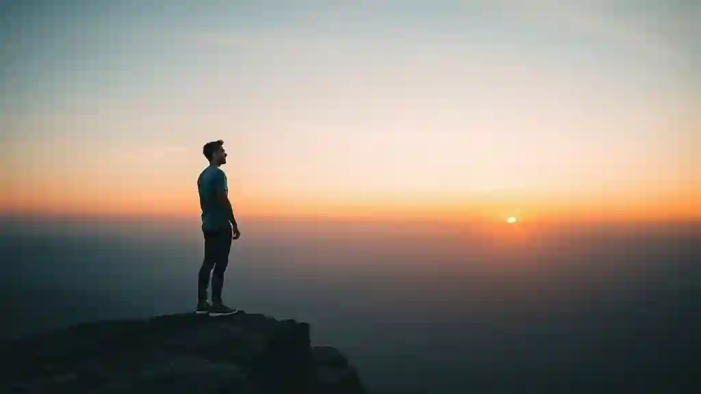 Person standing at sunrise overlooking the ocean, symbolizing peace and freedom after choosing not to text an ex again.