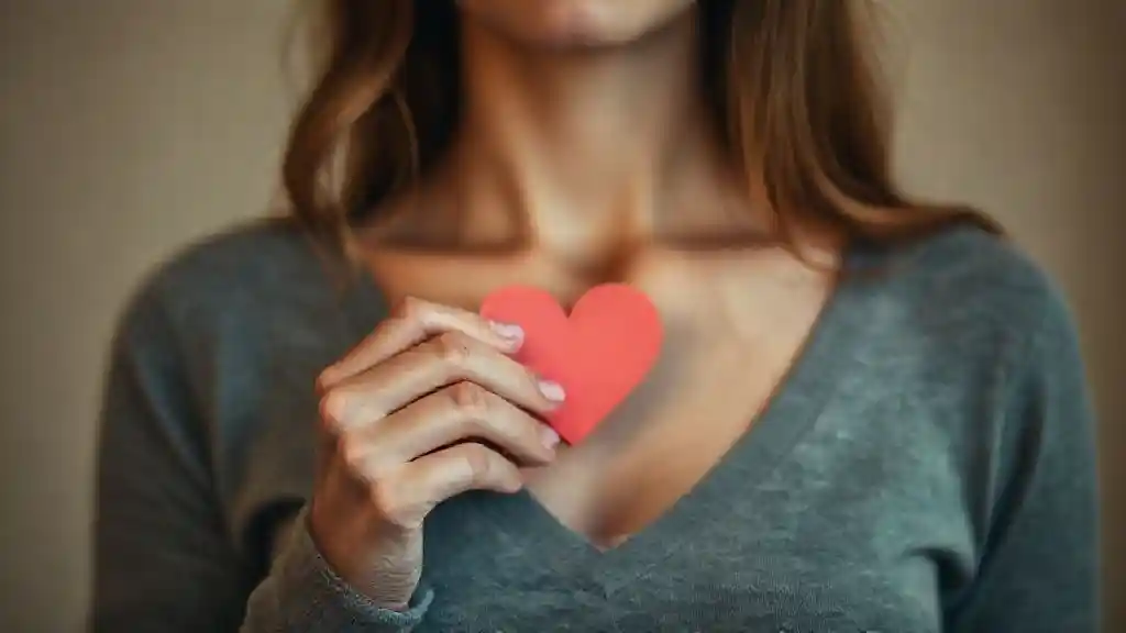 Woman holding a small paper heart symbolizing fear of heartbreak and hidden emotions.